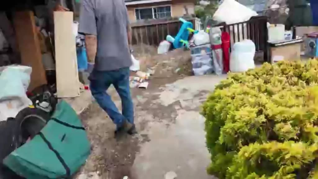 Hauler clearing bins, boxes and household clutter from the side yard of a single-story home