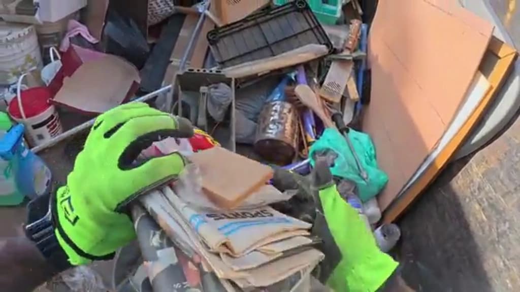 Gloved hands sorting cardboard and household items from a load into separate piles for donation and recycling