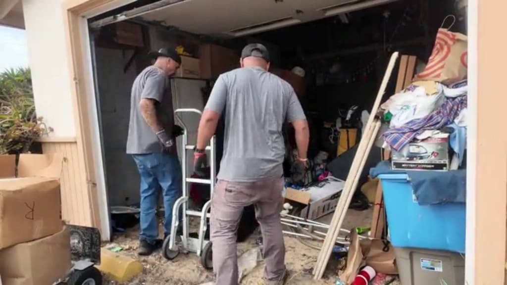 Two haulers moving a heavy item onto an appliance dolly inside a Hemet garage