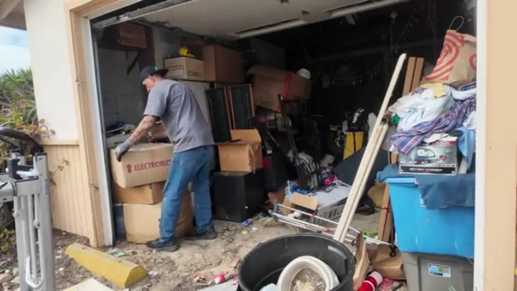 Hauler sorting boxes and household items in a garage before the load is split for donation and recycling