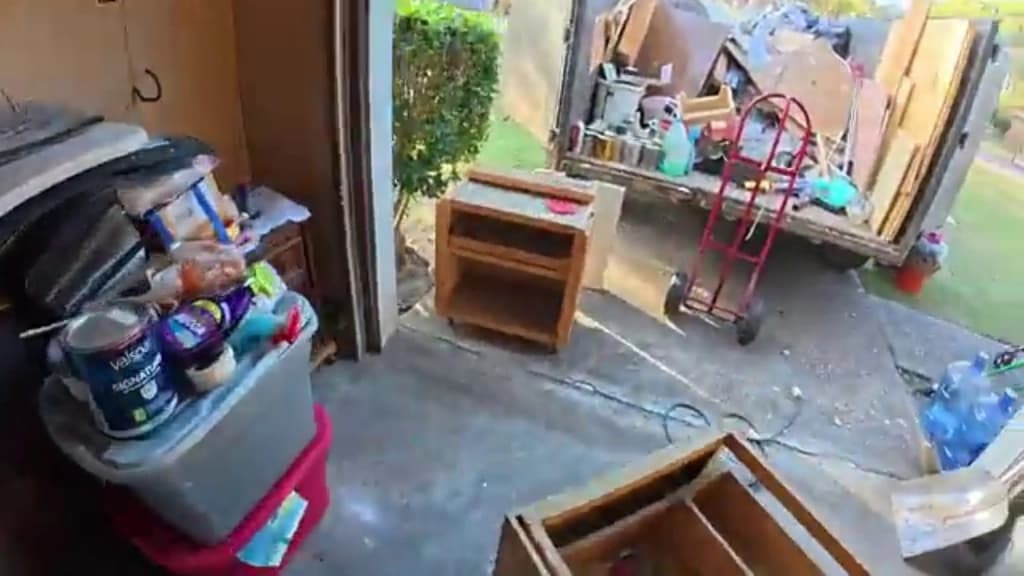 Sofas and dressers loaded onto a trailer outside a Hemet garage