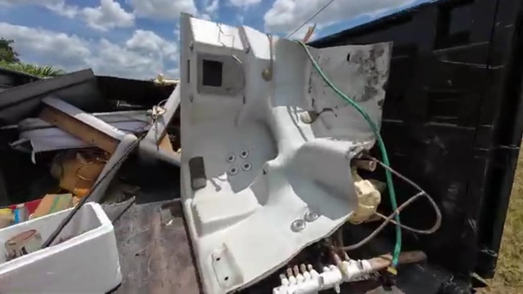 Cut-apart hot tub shell and plumbing loaded into a junk hauling truck