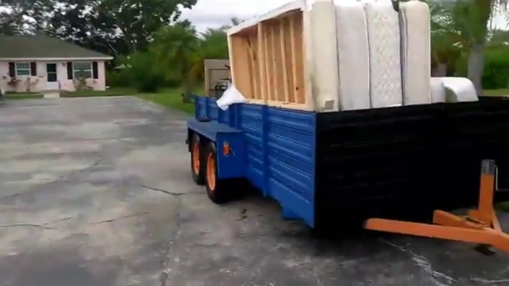 Mattresses and a box spring stacked on a hauling trailer for recycling
