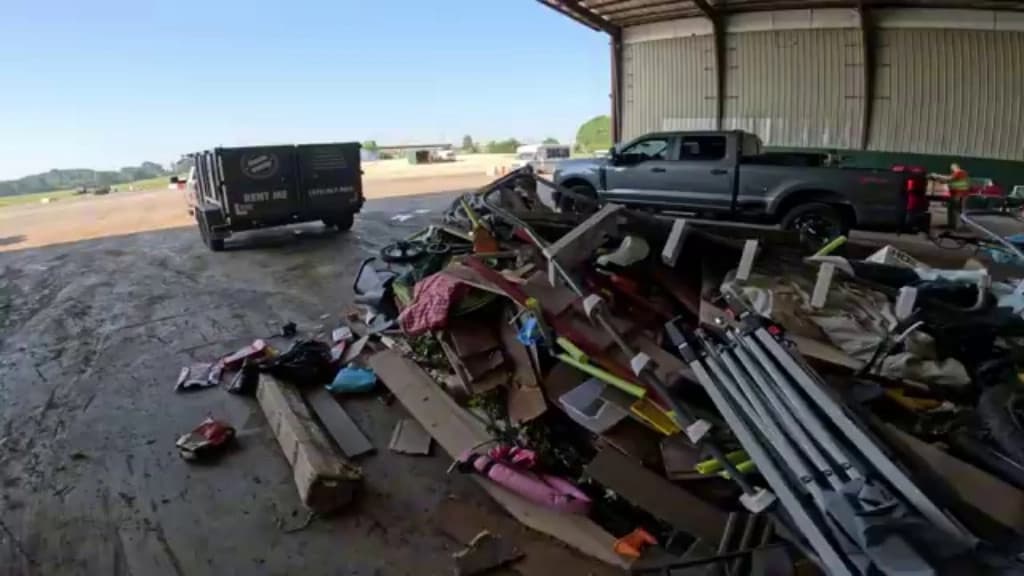 Debris and scrap cleared from a warehouse and staged beside a disposal truck